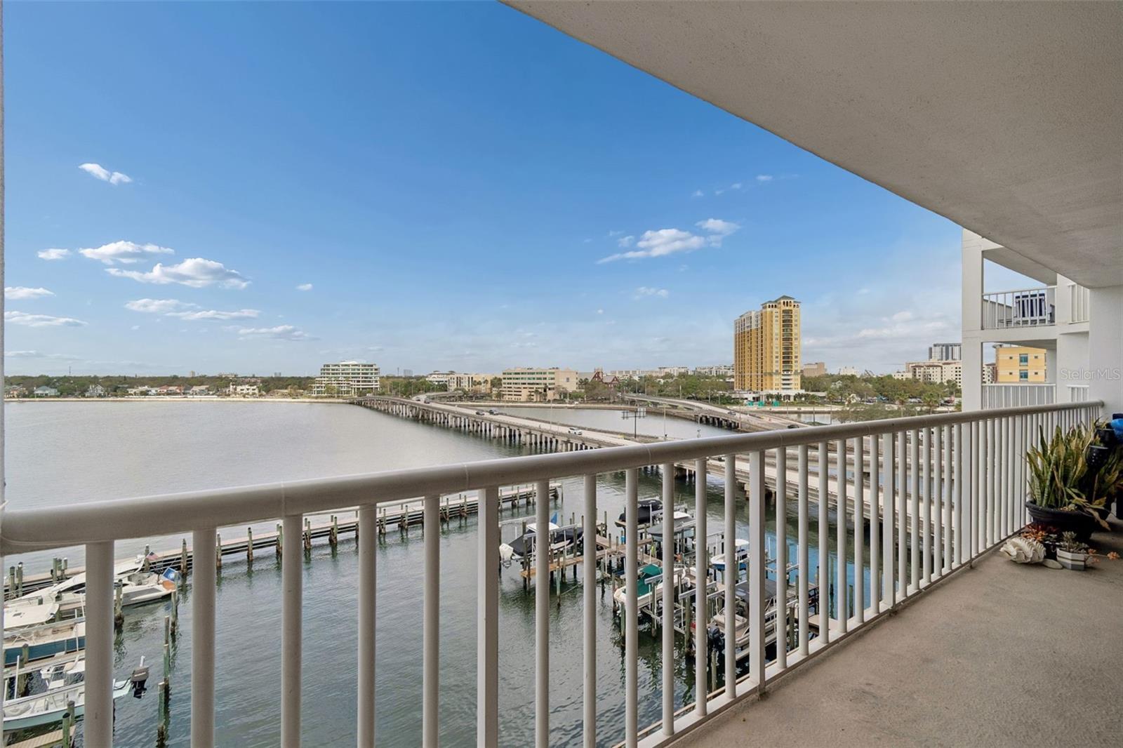 Condo balcony overlooking a marina, bridge, and distant city skyline.
