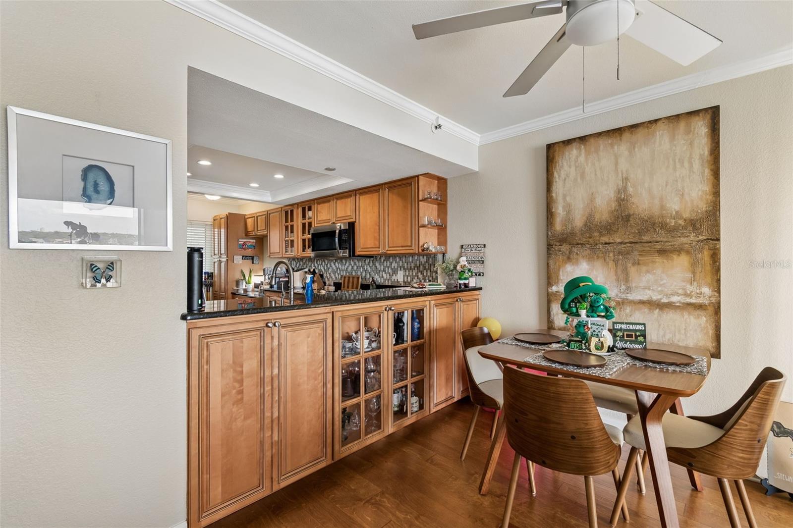 Kitchen and dining area with warm wood cabinets, mosaic backsplash, and a set dining table.