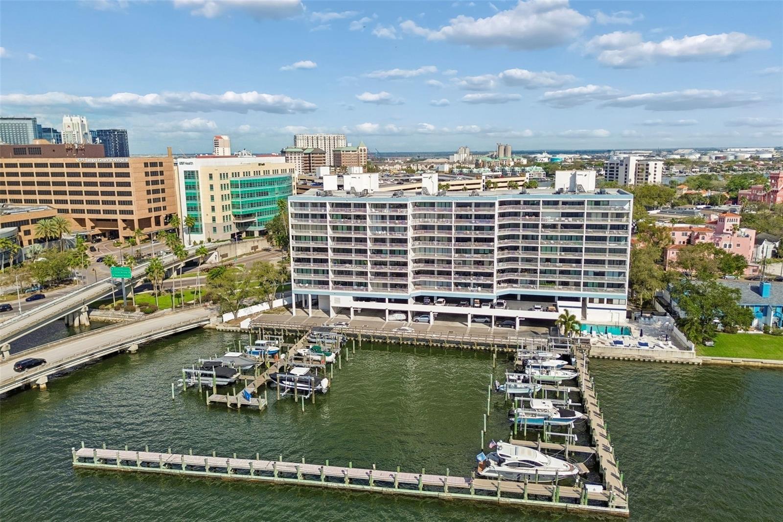 Waterfront condominium beside a marina, with boats in the docks and Tampa buildings beyond.