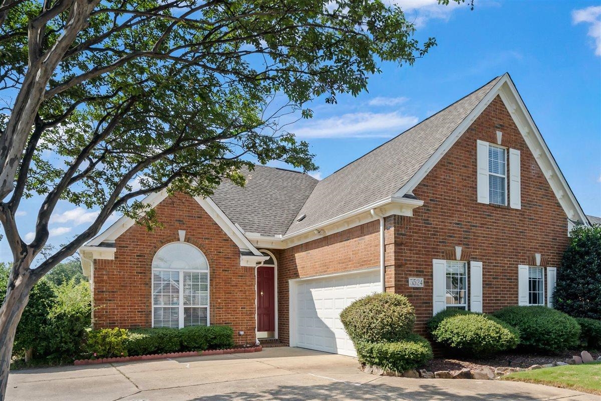 Red-brick house with a steep gabled roof, white garage door, and arched front window.