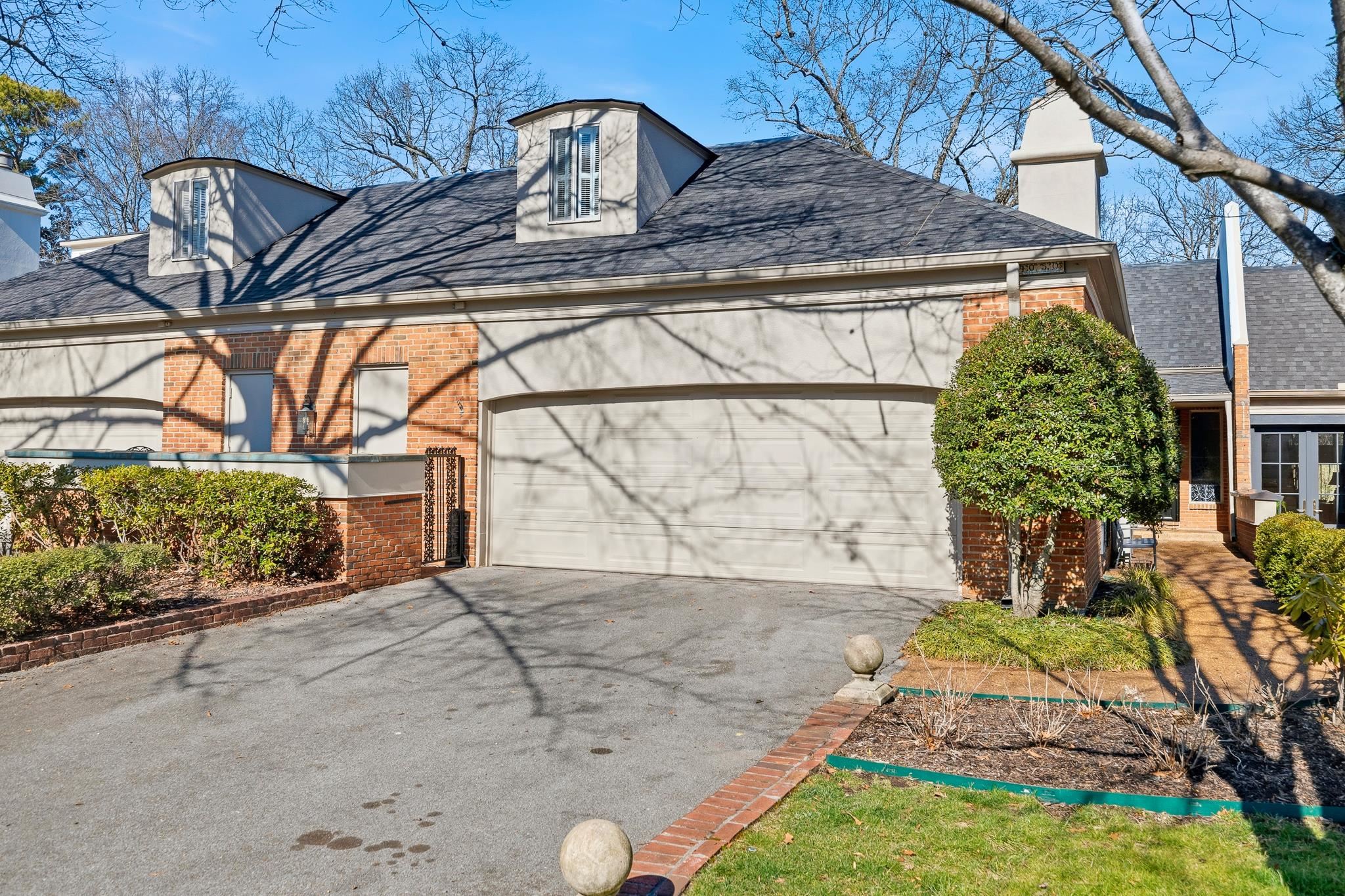 Home exterior with brick accents, two roof dormers, and a large attached garage.