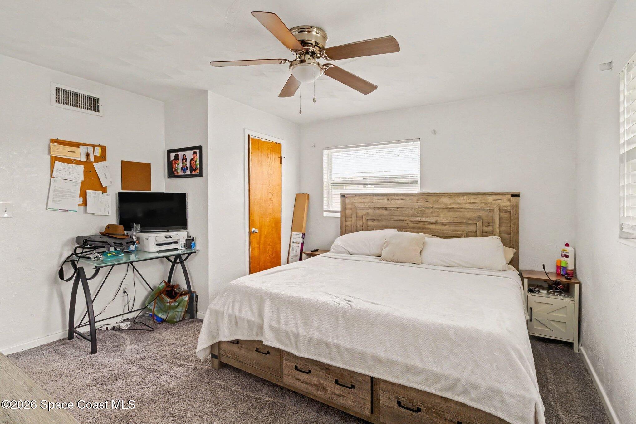 Bedroom with a large wooden storage bed, white bedding, and a ceiling fan.