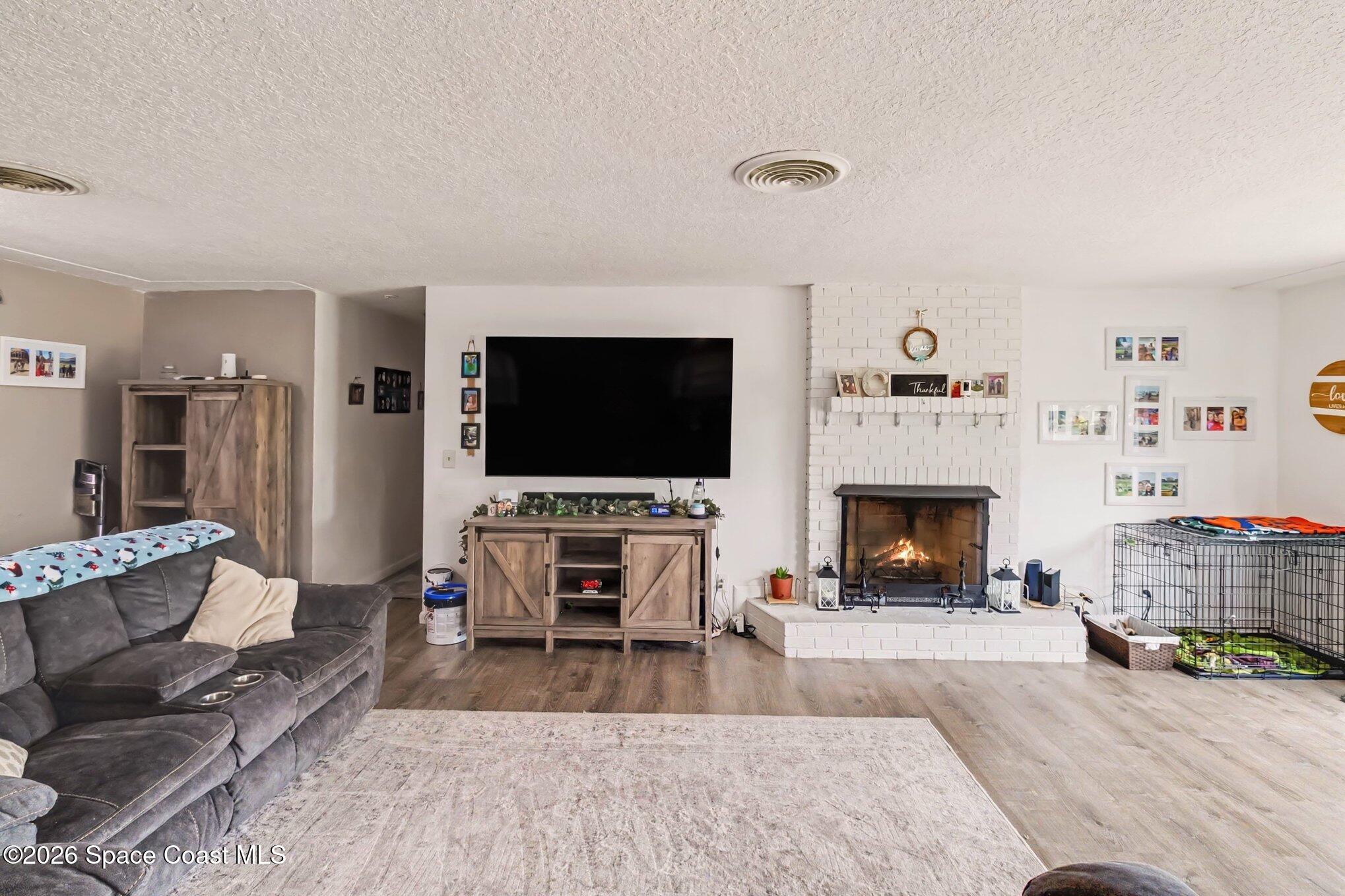 Living room with a white brick fireplace, mounted television, and gray sectional sofa.