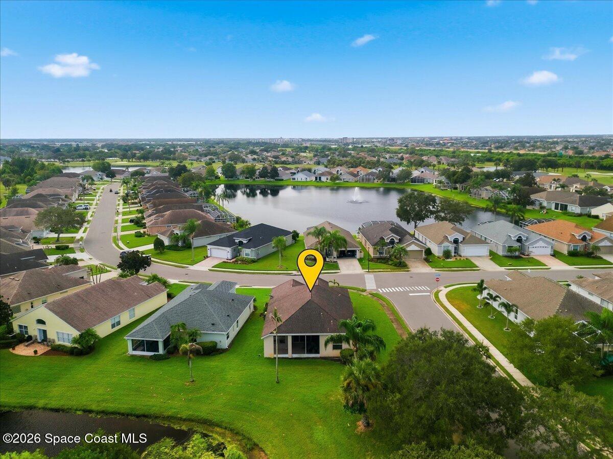 Aerial view of a marked home beside a neighborhood pond with a fountain.