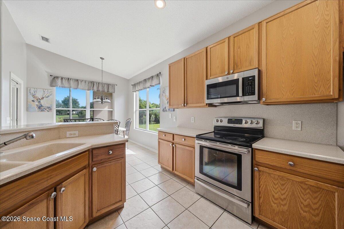 Kitchen with oak cabinets, stainless-steel appliances, and windows overlooking a green yard.