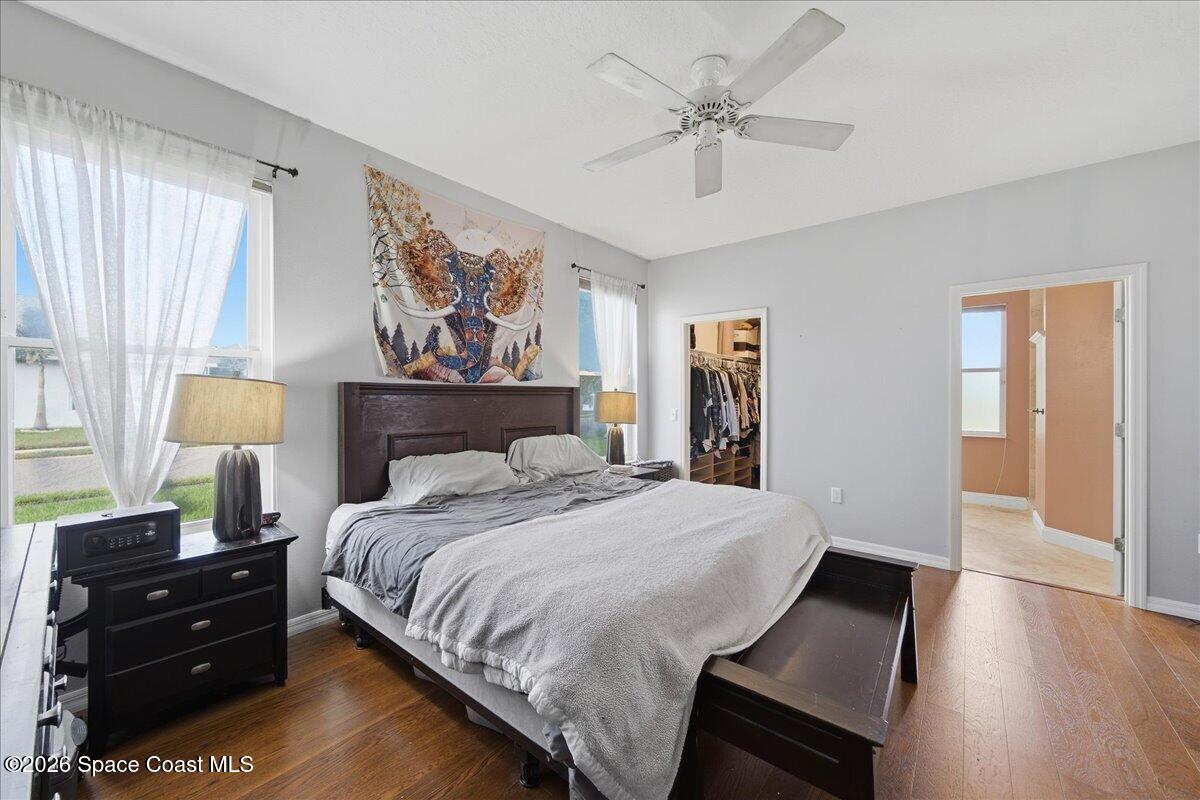 Furnished bedroom with a large bed, dark wood furniture, and sheer-curtained windows.