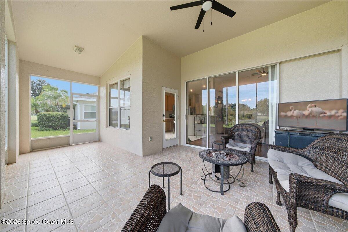 Screened patio with wicker seating and patterned tile flooring, opening onto a lawn.