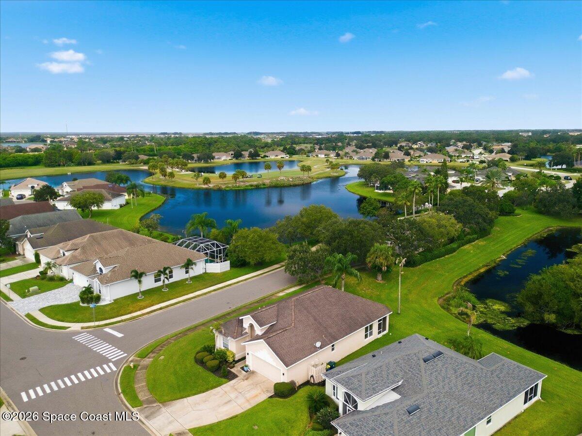 Aerial view of homes around a lake, with a house and intersecting streets in the foreground.