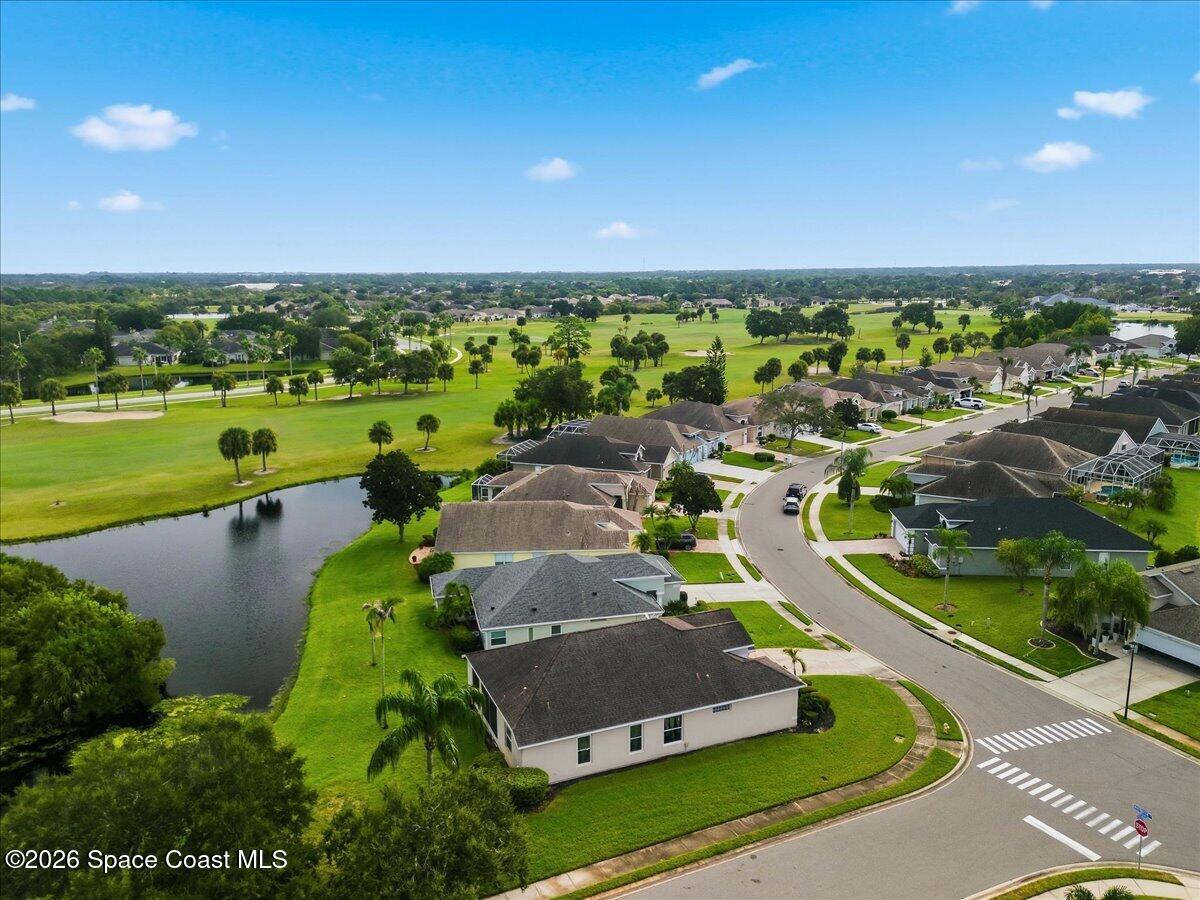 Aerial view of homes along a curved street beside a pond and golf course.