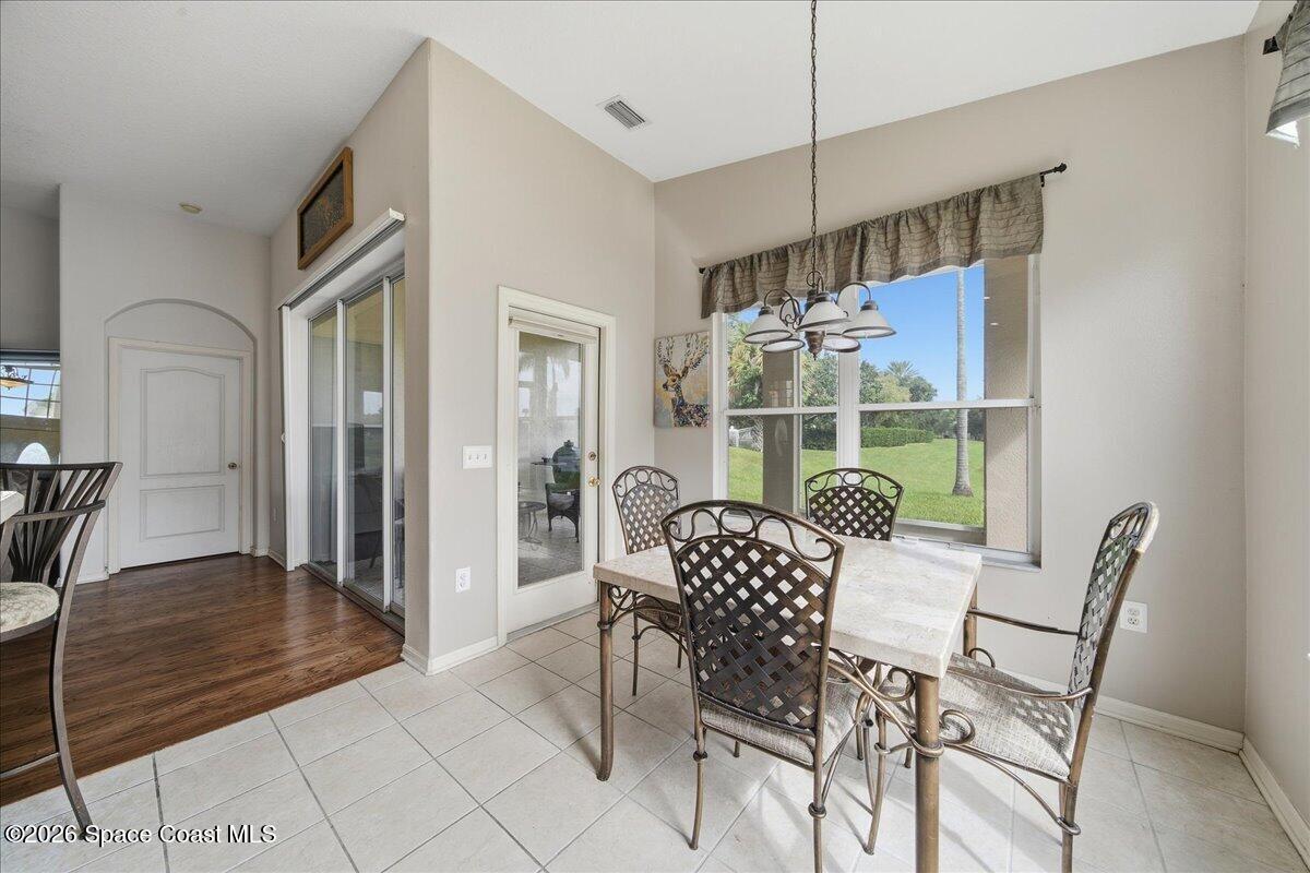 Dining area with a stone-top table, metal chairs, and a large window overlooking a lawn.