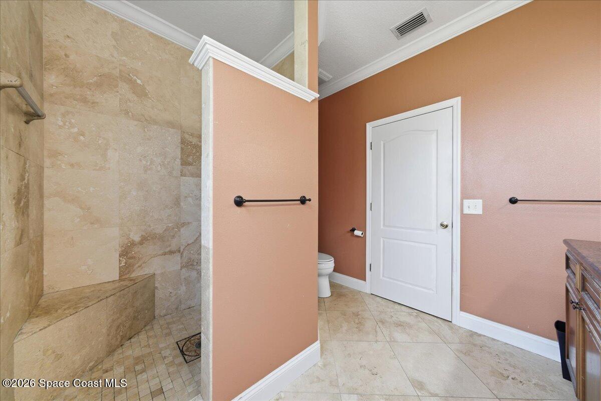 Bathroom with a stone-tile walk-in shower, built-in bench, and peach walls.