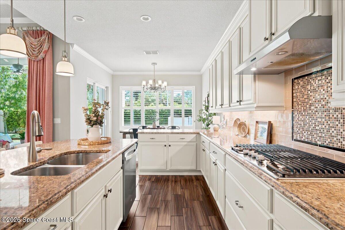 Kitchen with white cabinets, granite counters, a gas range, and a double sink.