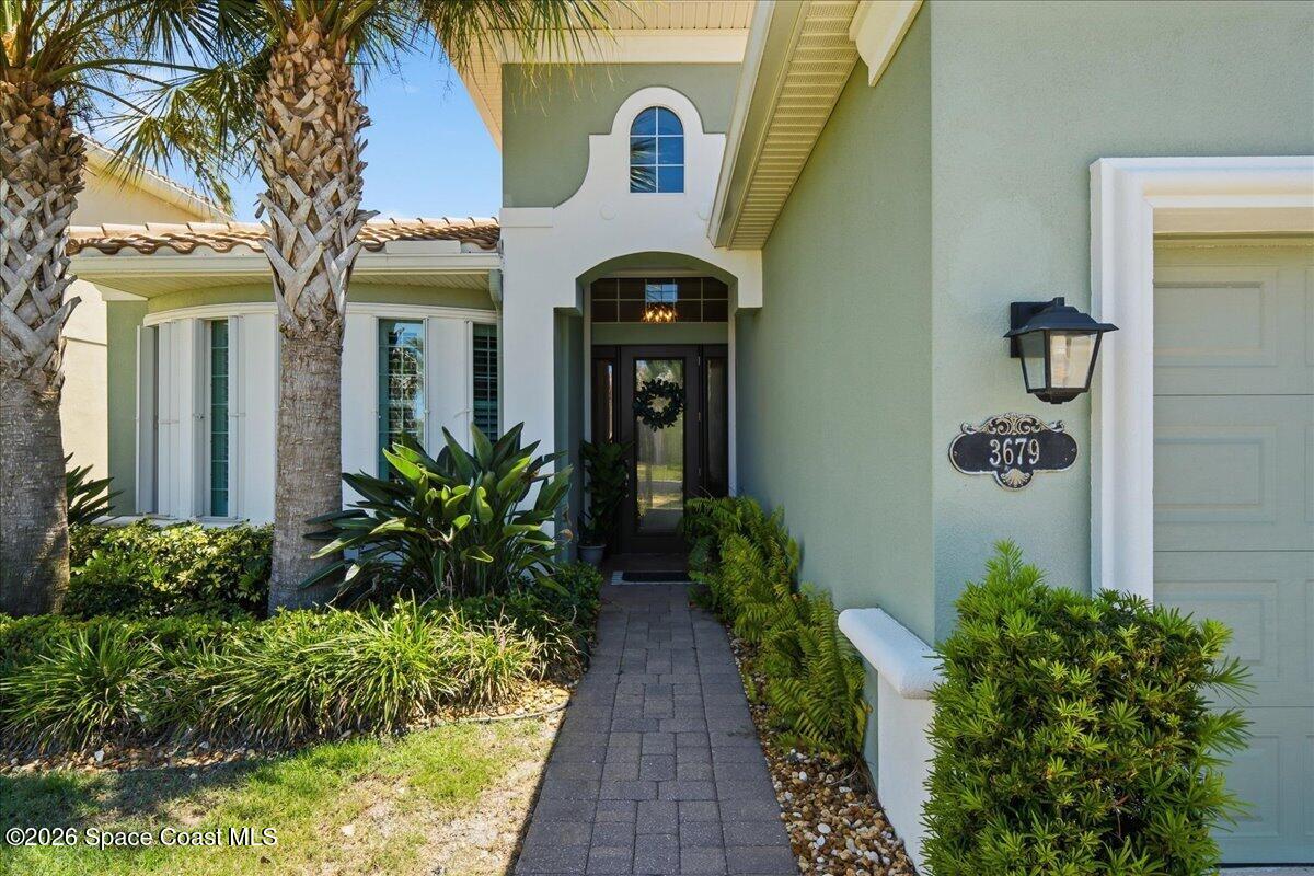 Home entrance with a paved walkway, tropical landscaping, and a decorative 3679 address plaque.