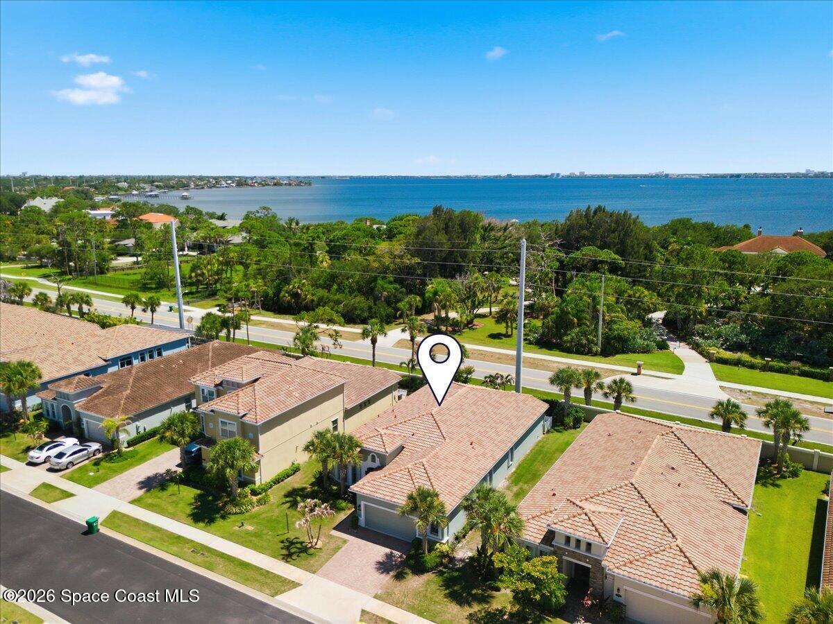 Aerial view of a tile-roofed home near the bay, marked by a location pin.