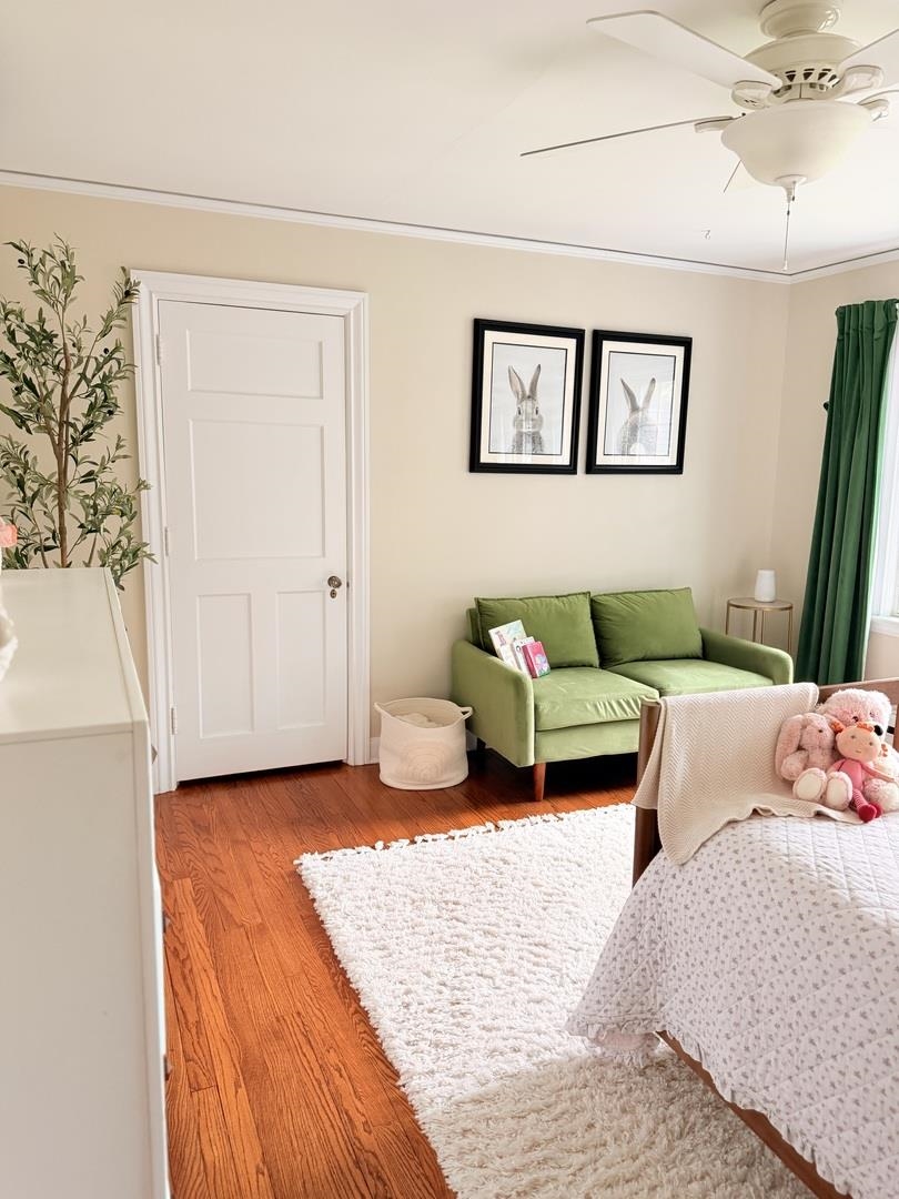 Bedroom with a green loveseat, framed rabbit prints, and a white rug beside the bed.