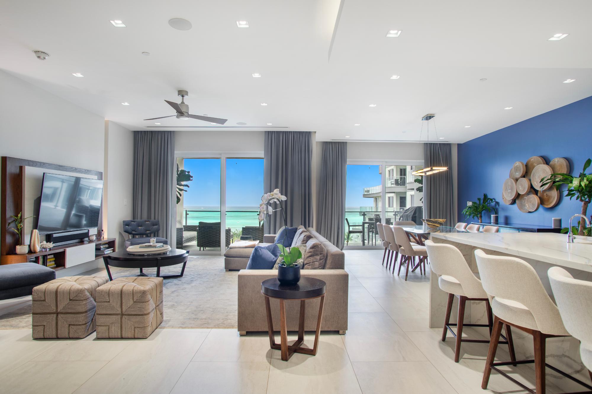 Open-plan living room and dining area with a blue accent wall and ocean views.