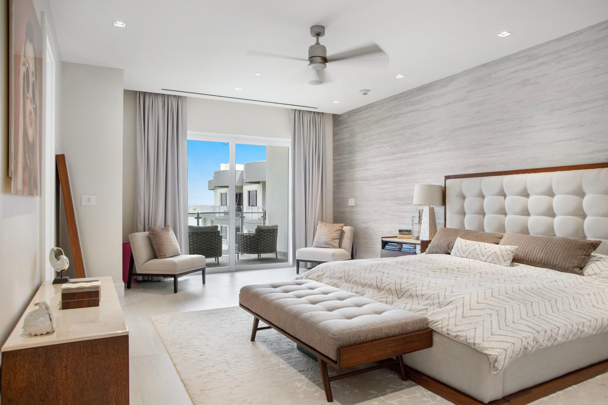 Modern bedroom with a tufted bed and sliding glass doors opening onto a balcony.