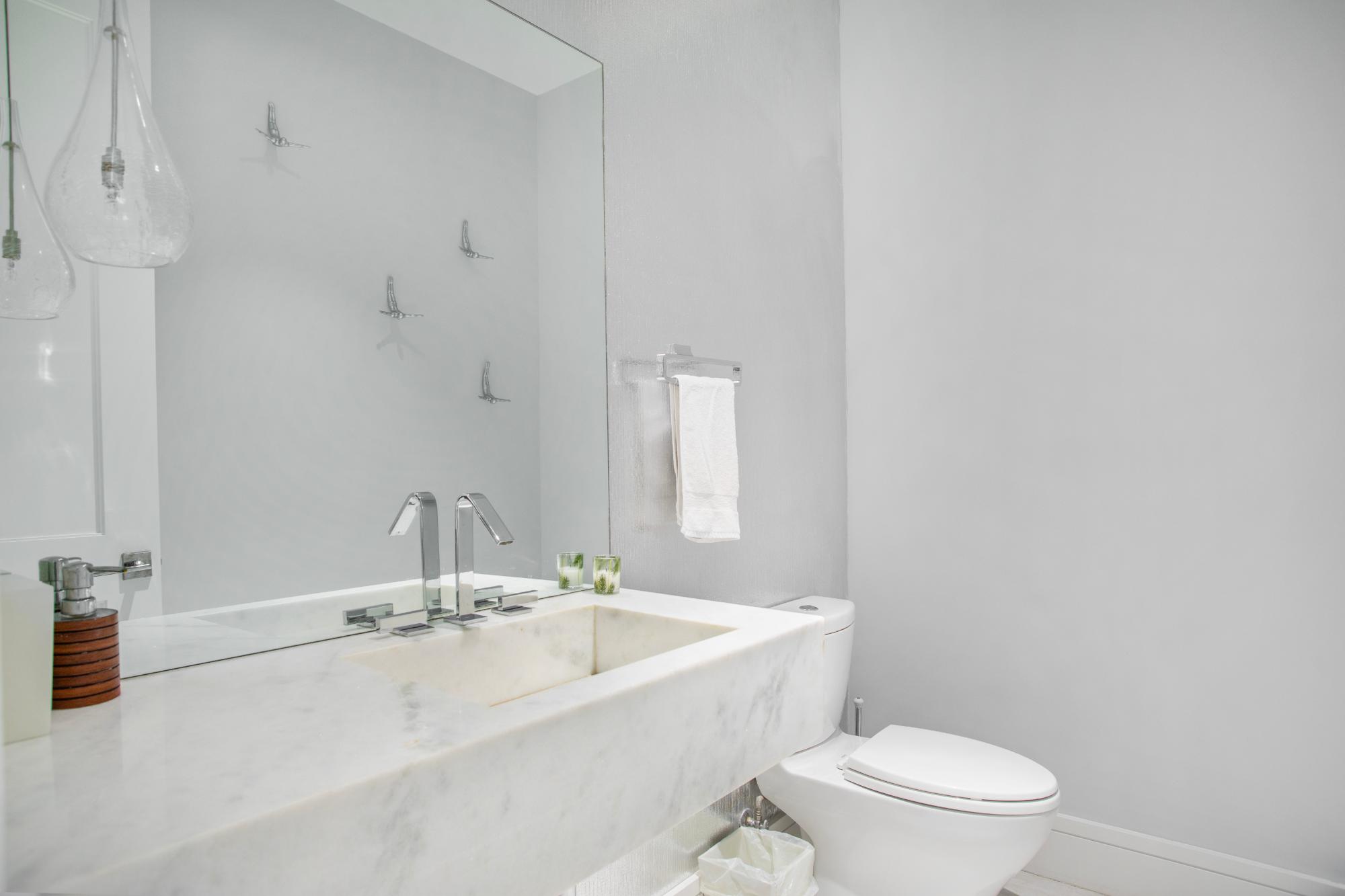 Modern bathroom with a long marble vanity, chrome faucets, and a large mirror.