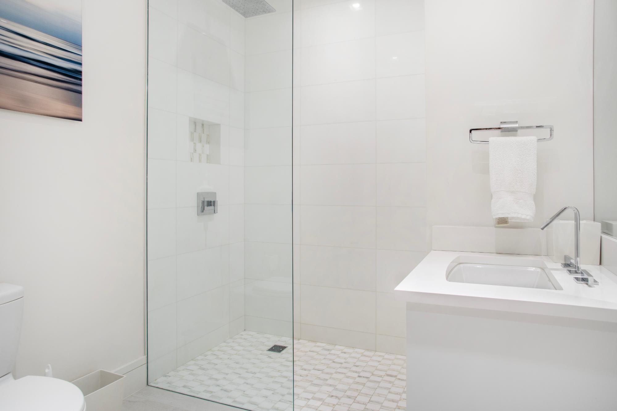 Modern white bathroom with a glass walk-in shower and sleek vanity.