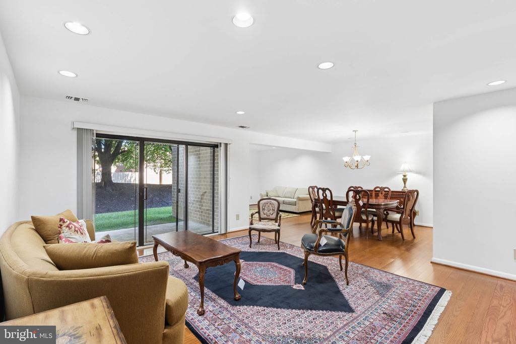 Living and dining area with hardwood floors, patterned rug, and sliding glass doors to a grassy yard.