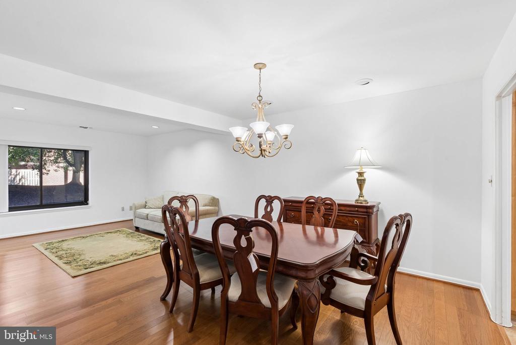 Dining room with a dark wood table and chandelier beside a sitting area and large window.