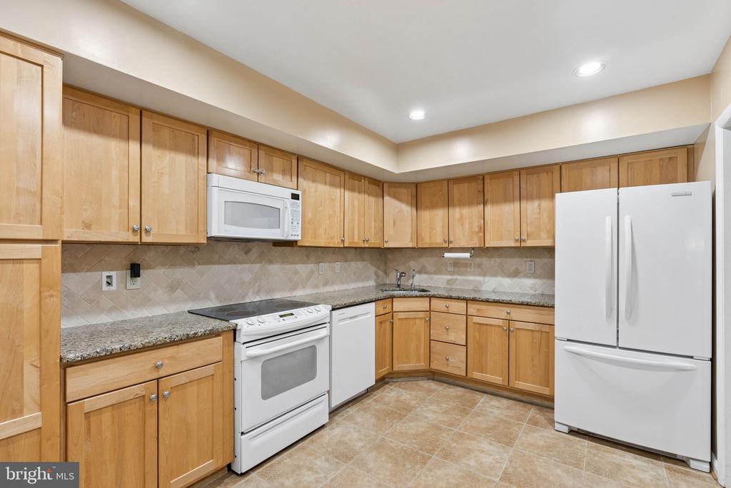 Kitchen with light wood cabinetry, granite counters, and white appliances.