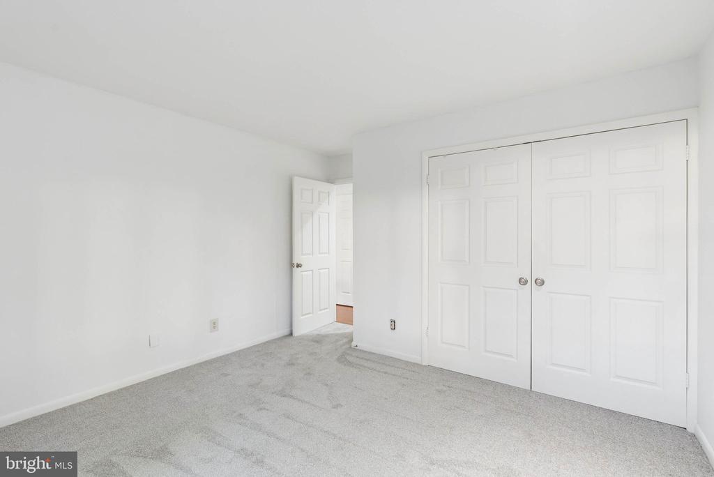 Empty bedroom with gray carpet, white walls, and a double-door closet.