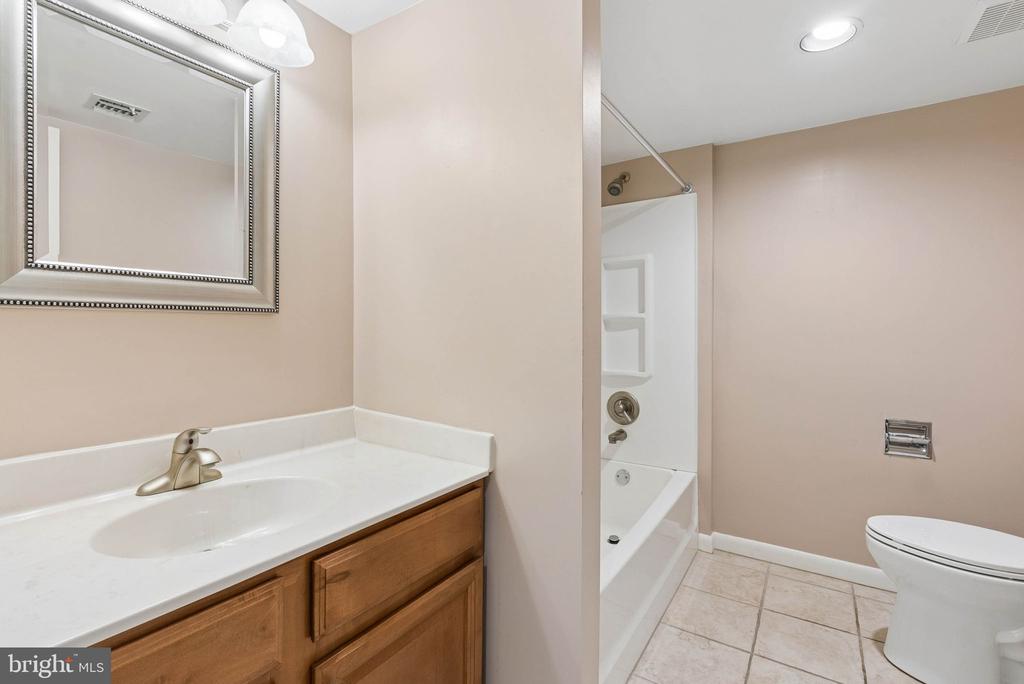 Bathroom with a wood vanity and framed mirror beside a tub and shower.