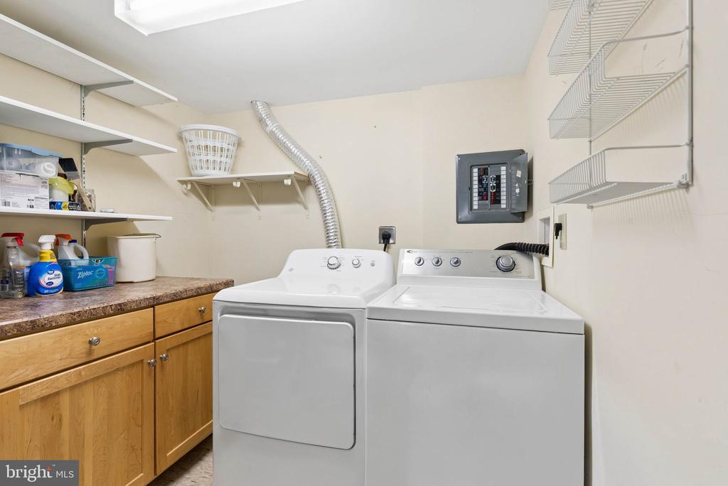 Laundry room with a washer and dryer, wooden cabinets, and open shelving.