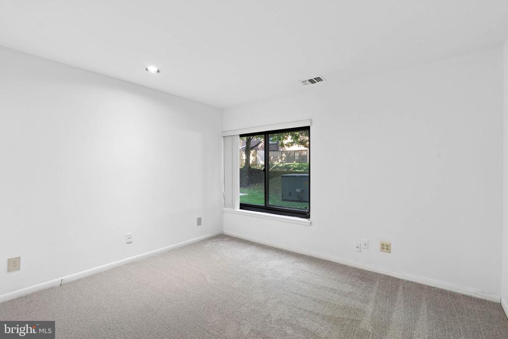 Empty carpeted room with a sliding window overlooking a yard.