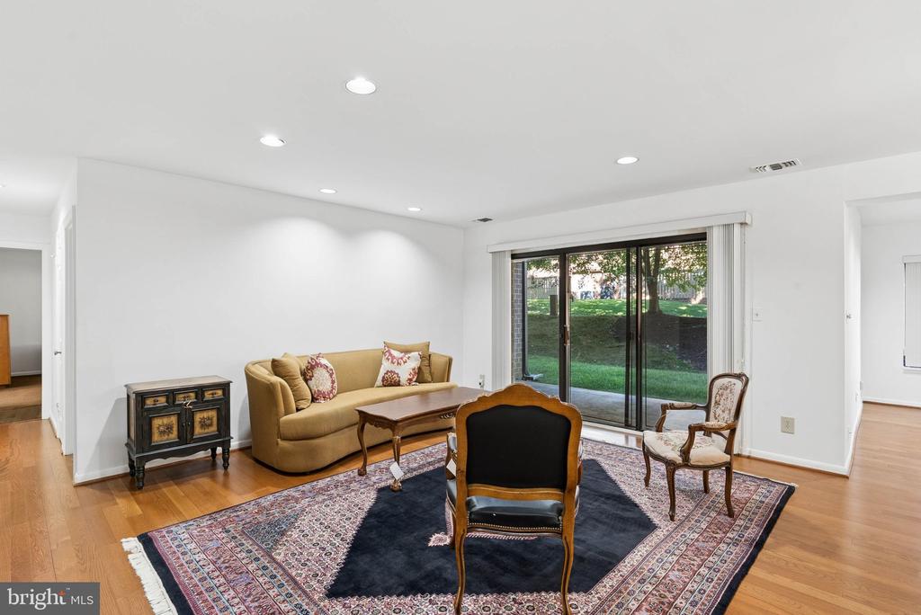 Living room with a tan sofa, patterned rug, and sliding glass doors overlooking a grassy area.