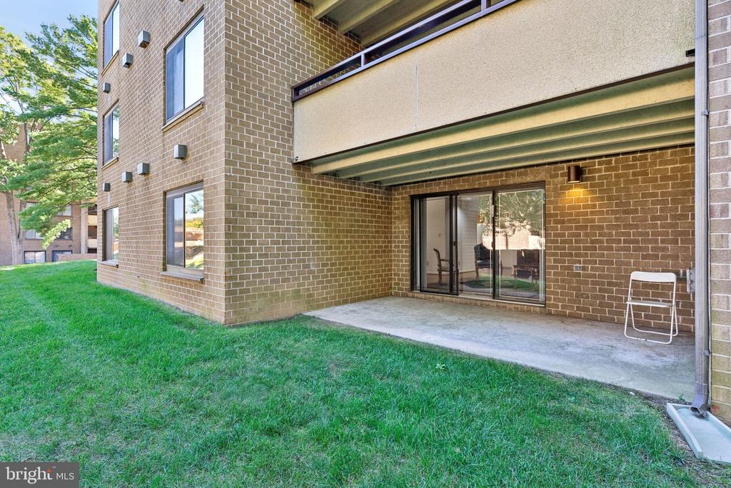 Brick building with a covered patio, sliding glass doors, and lawn.
