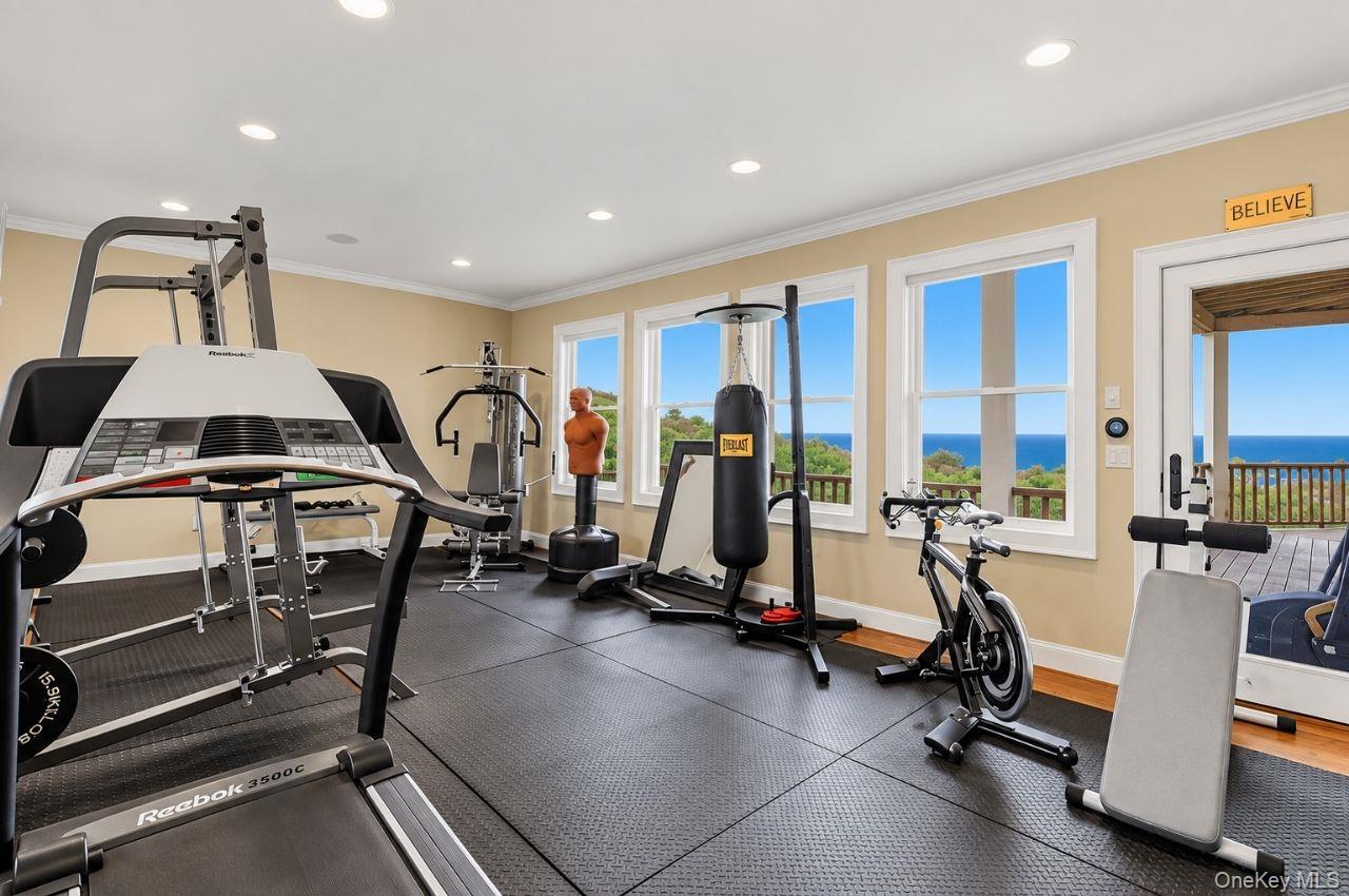 Home gym with exercise equipment and ocean views through large windows.