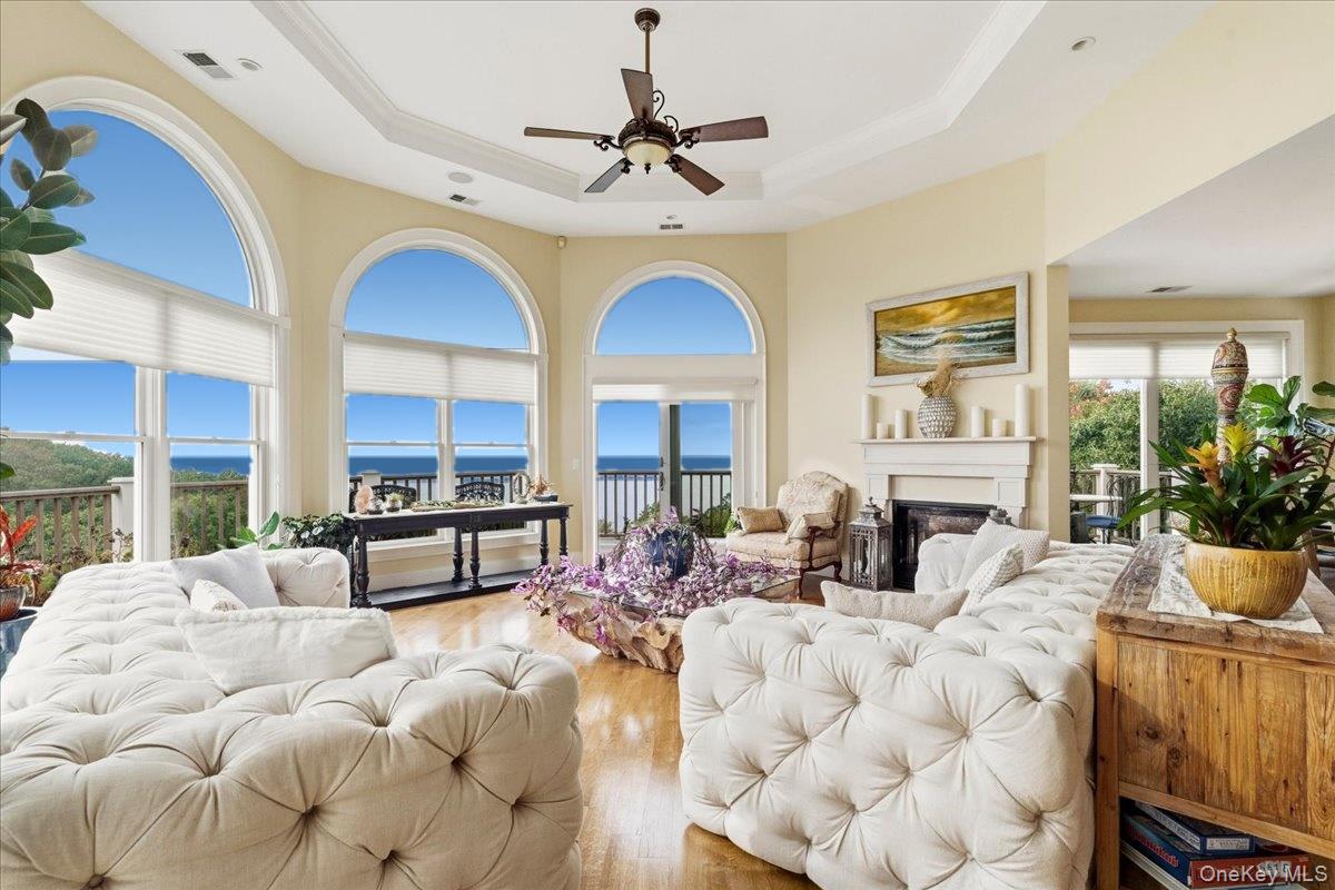 Living room with arched ocean-view windows, tufted white sofas, and a fireplace.