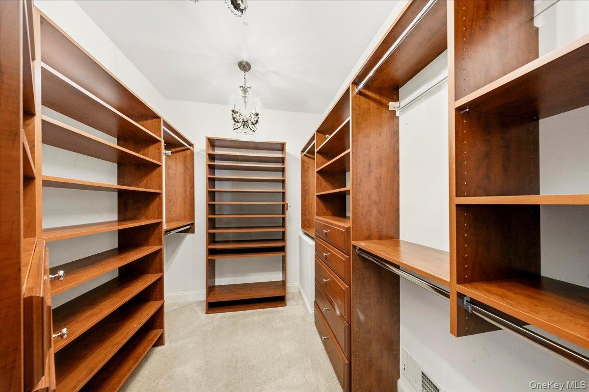 Walk-in closet with extensive wood shelving, drawers, and hanging rods.