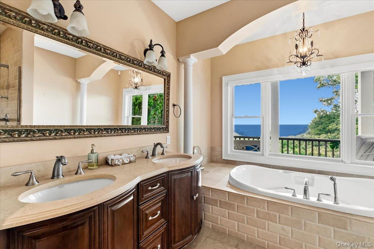 Bathroom with a double-sink vanity and soaking tub overlooking the ocean.