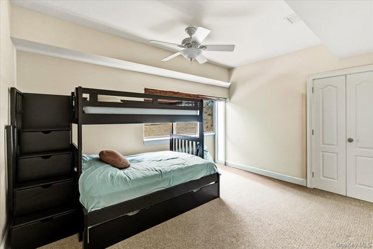 Bedroom with a black bunk bed, pale aqua bedding, beige carpet, and a ceiling fan.