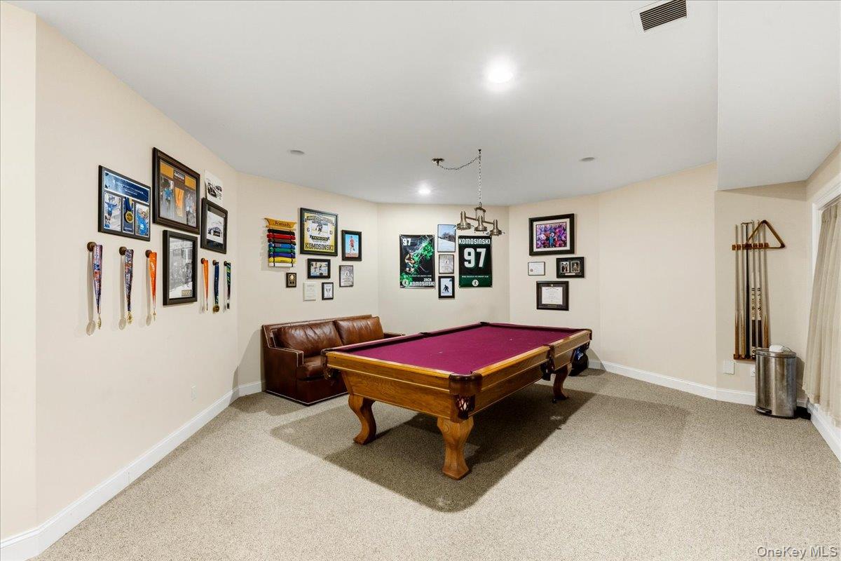Game room with a magenta-felt pool table, leather sofa, and sports memorabilia.