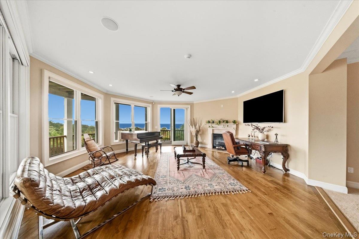 Living room with a piano, fireplace, and expansive windows overlooking the water.
