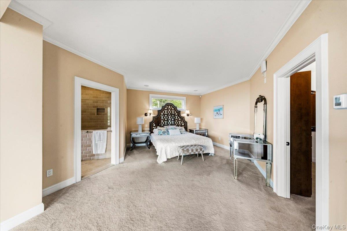 Furnished bedroom with an ornate dark headboard, carpeted floor, and adjoining tiled bathroom.