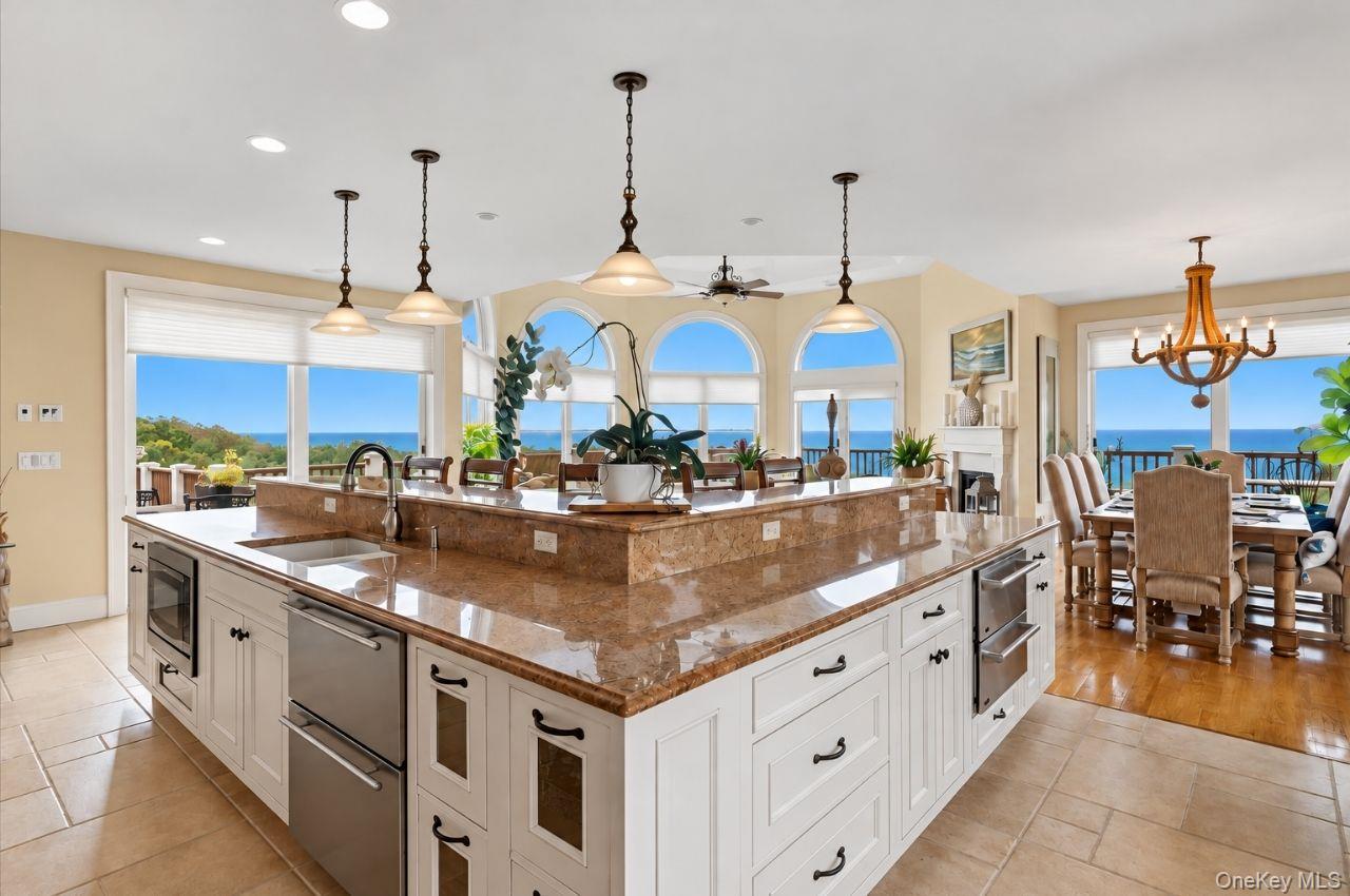 Kitchen with a large stone island, arched windows, and ocean views.