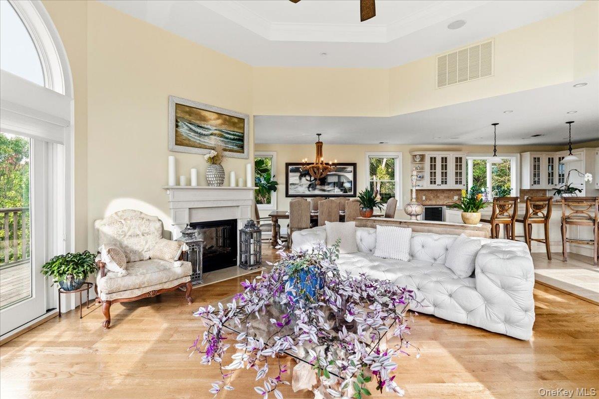 Living room with a white sectional, fireplace, hardwood floors, and open kitchen.