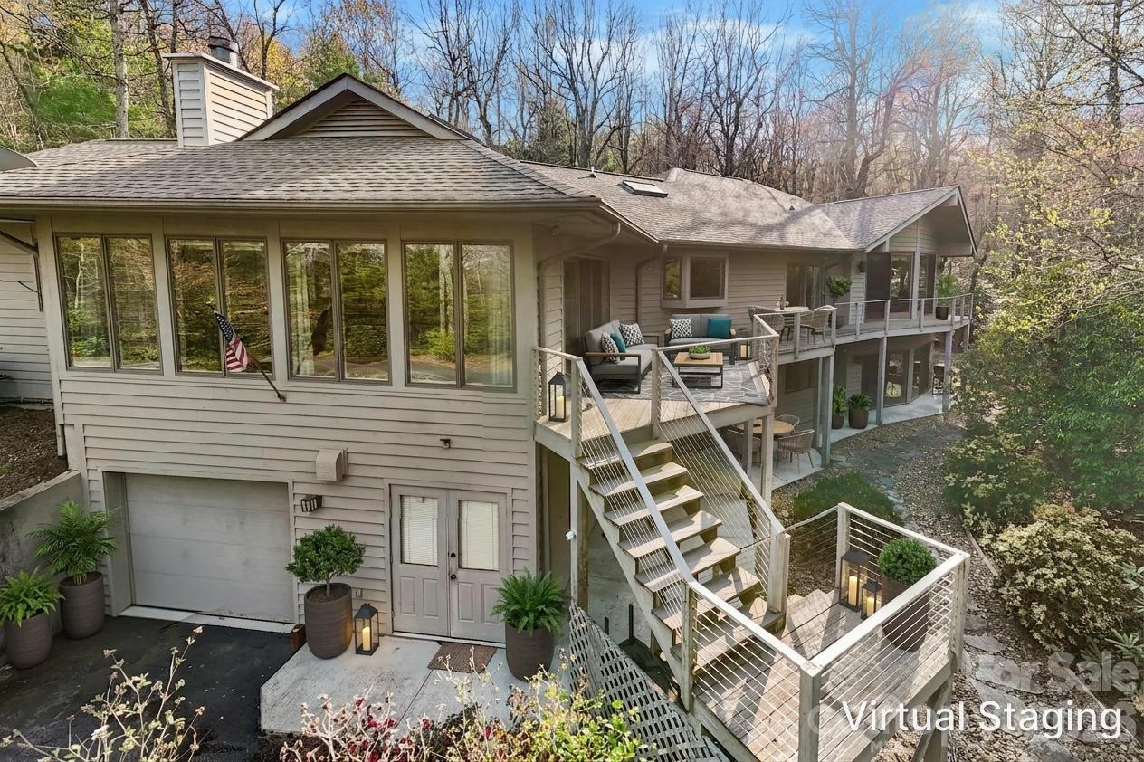 Home with multi-level decks, outdoor seating, and wooded surroundings.