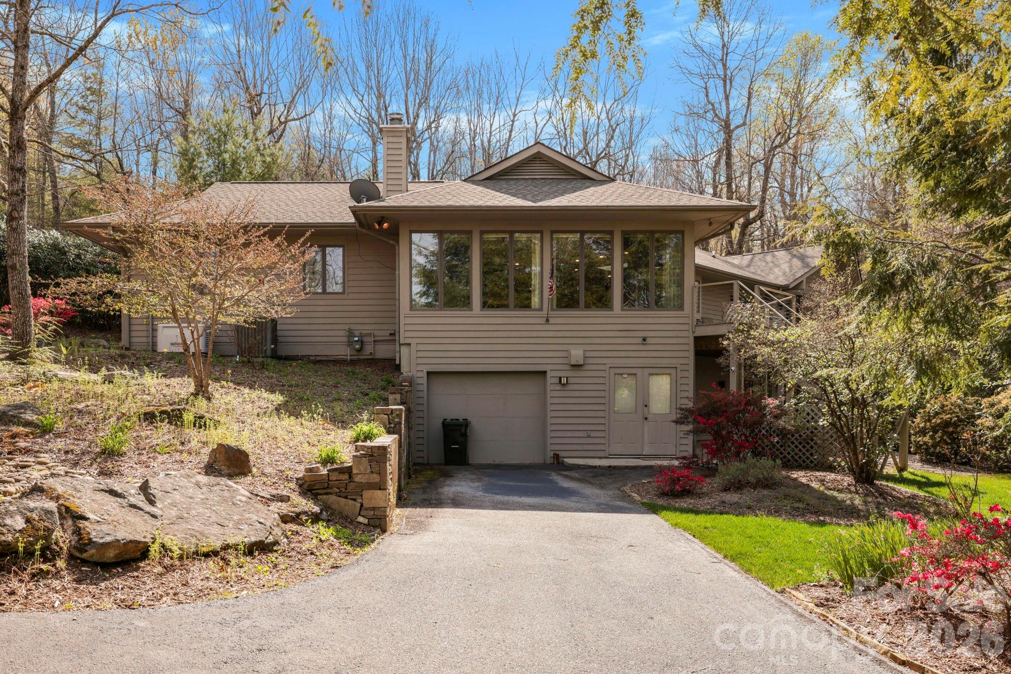 Taupe-sided house with a garage, broad front windows, and a landscaped driveway.