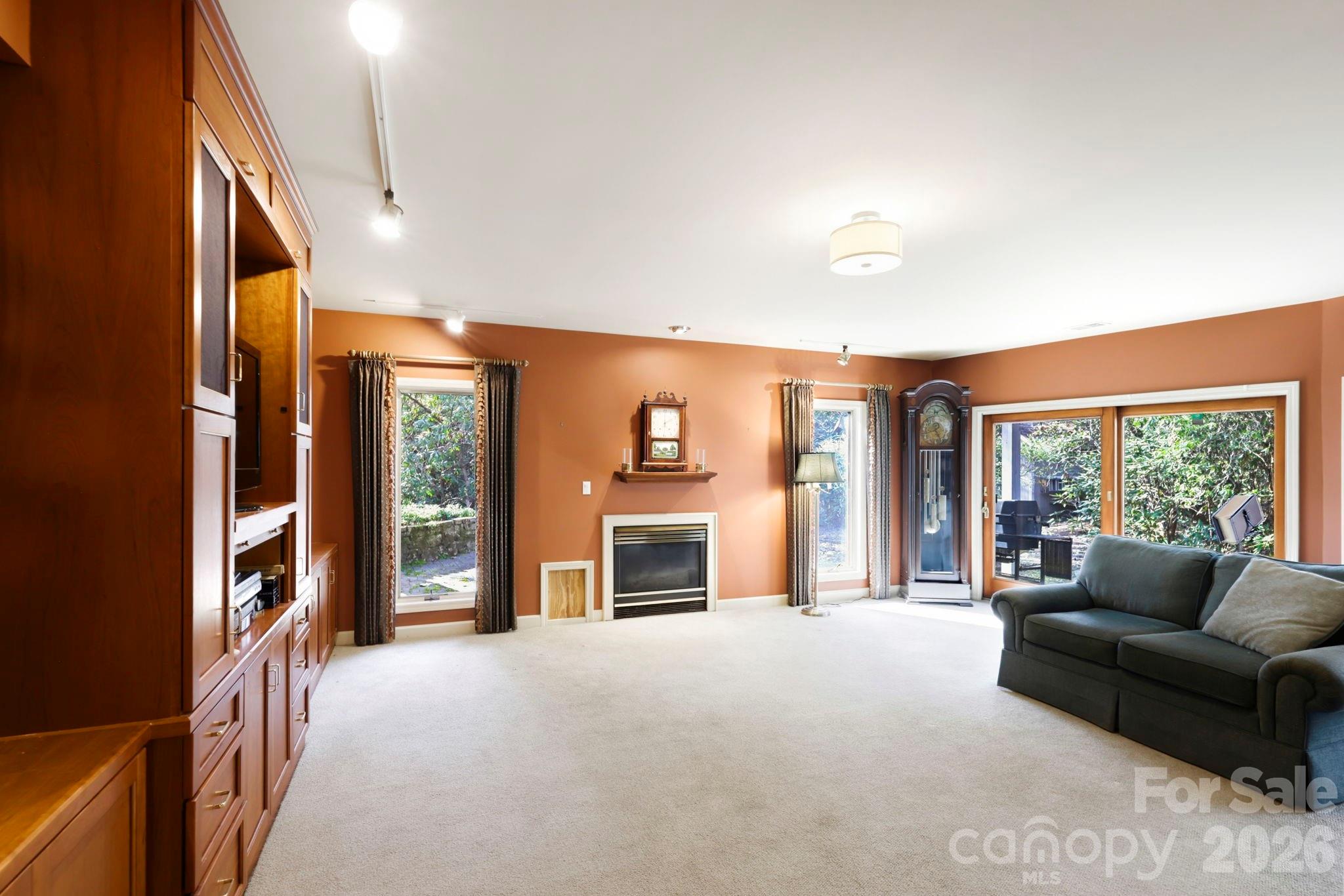 Living room with built-in wood cabinetry, a fireplace, grandfather clock, and sliding glass doors.