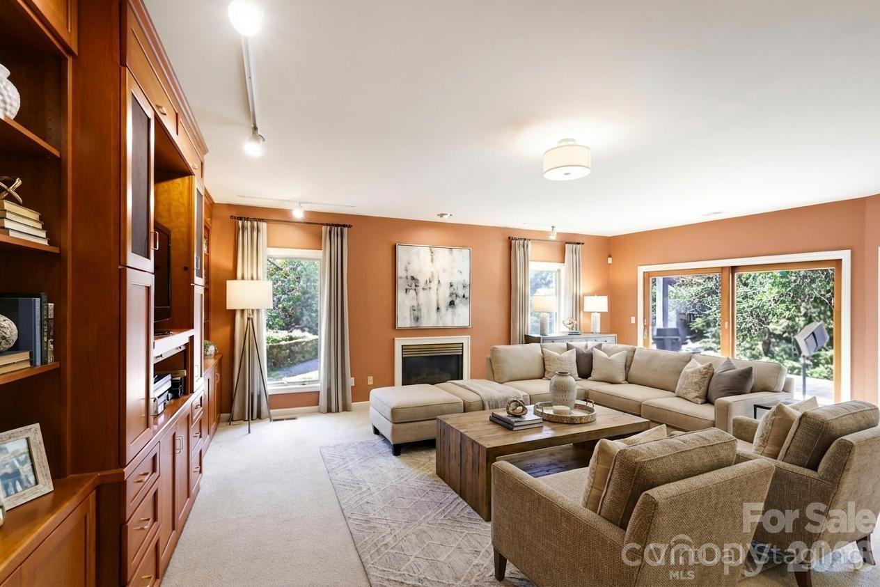 Living room with built-in wood cabinetry, a fireplace, and a beige sectional beside sliding glass doors.