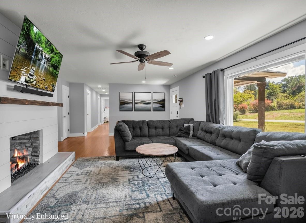 Living room with a large gray sectional, white fireplace, and sliding glass door overlooking the yard.