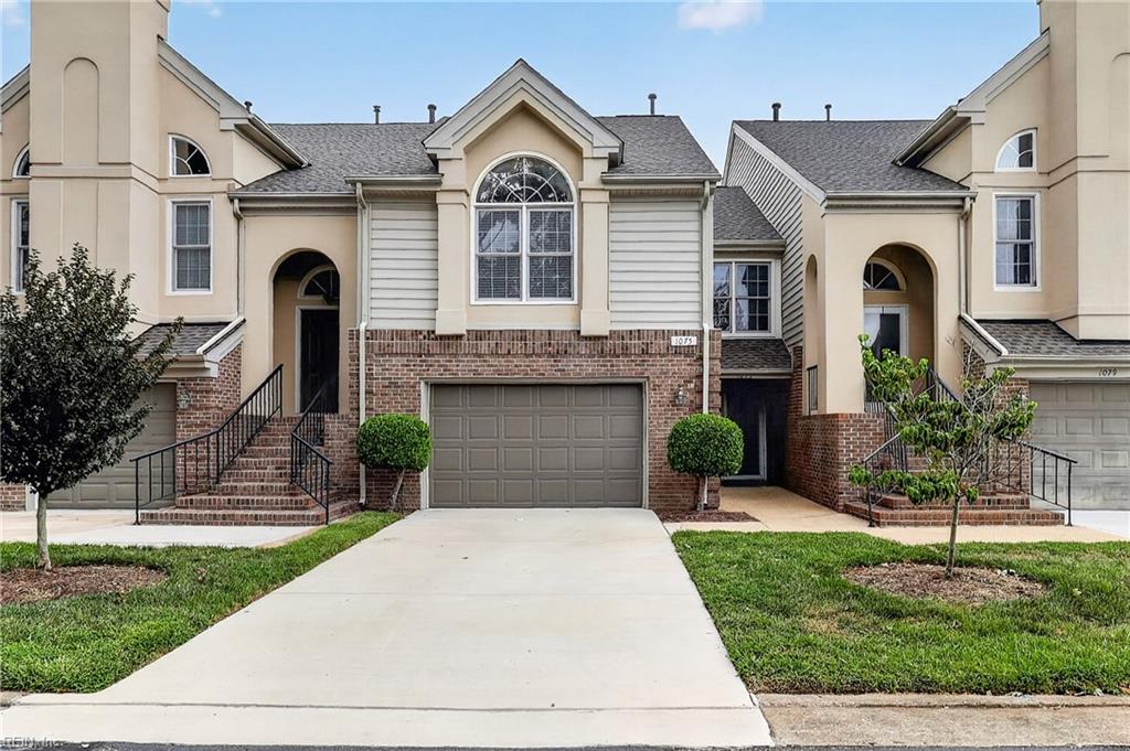 Attached townhouse with beige siding, brick accents, and a central garage and driveway.