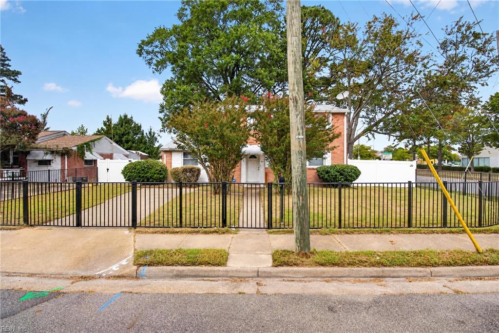 Single-story brick and white-sided home behind a black metal fence, with a utility pole in front.