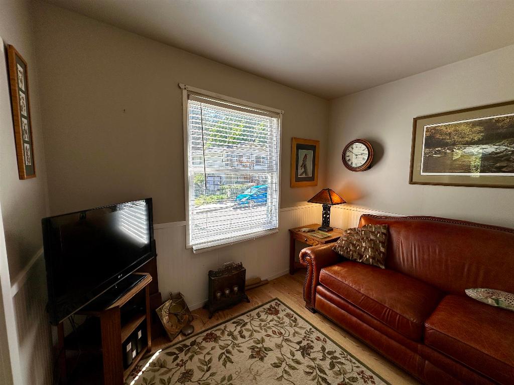Living room with a brown leather sofa, patterned rug, and window with blinds.
